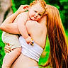 child, toddler, woman, red_hair, curly_hair, outdoor, nature, greenery, holding, toy_car, affection, portrait, casual_clothing, bare_shoulders, summer, daylight, happy, family, back_view, playful