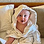 Dawson is registered to the contest to win money with this photo: baby, child, bathrobe, hood, white, bed, pillow, indoor, smiling, happy, blue_eyes, sitting, cute, skin, infant, blanket, cozy, young, person, portrait