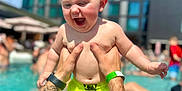 Dawson joined the competition — help win amazing prizes! baby, child, pool, water, tattoo, arms, swim_trunks, summer, outdoor, building, sky, happy, playing, person, sunlight, fun, vacation, holding, tattooed_arms, splash