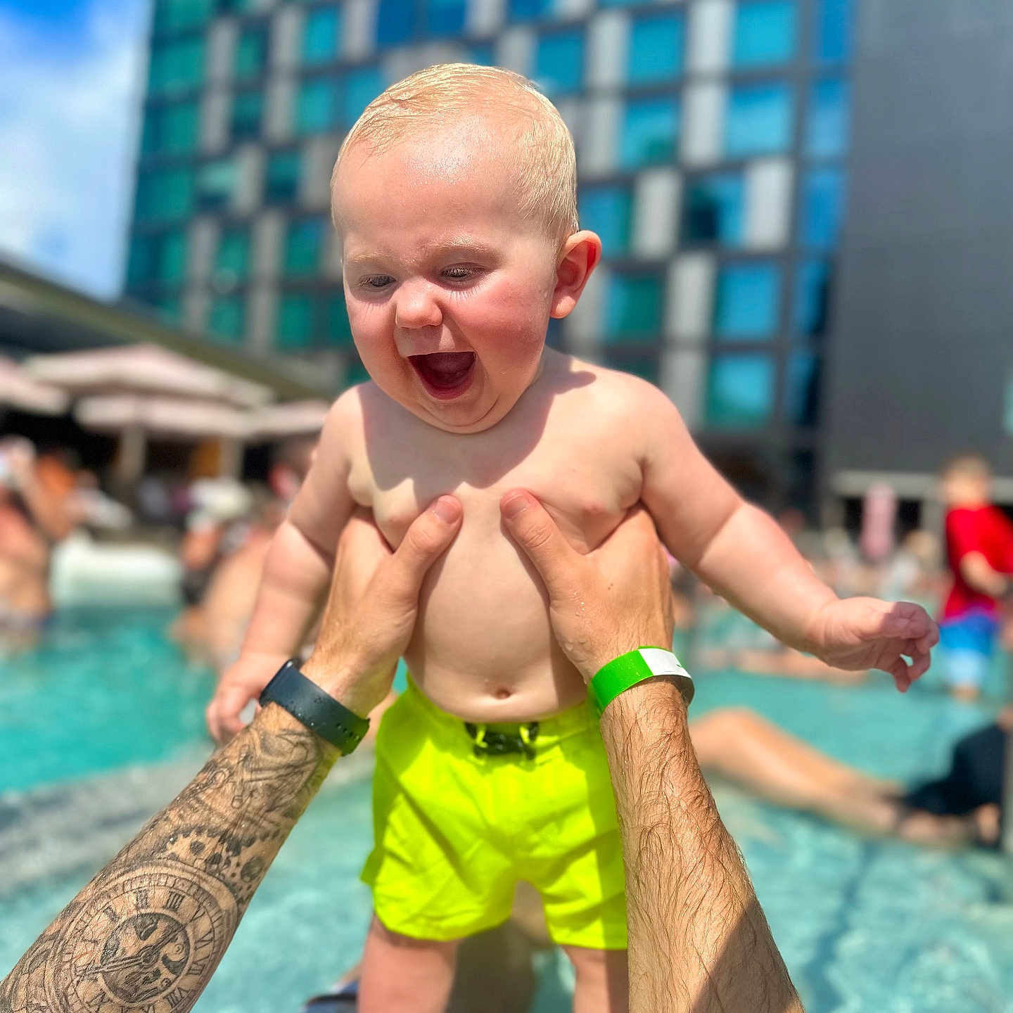 Dawson joined the competition — help win amazing prizes! arms, baby, building, child, fun, happy, holding, outdoor, person, playing, pool, sky, splash, summer, sunlight, swim_trunks, tattoo, tattooed_arms, vacation, water
