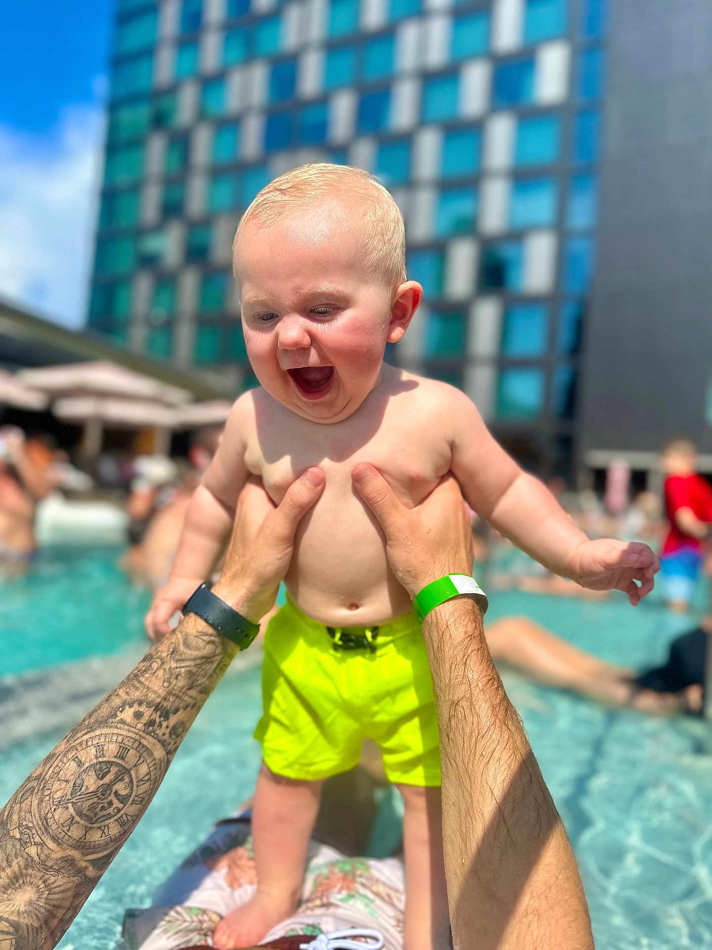 Dawson joined the competition — help win amazing prizes! baby, child, pool, water, tattoo, arms, swim_trunks, summer, outdoor, building, sky, happy, playing, person, sunlight, fun, vacation, holding, tattooed_arms, splash