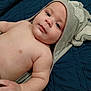 Braxton is registered to the contest to win money with this photo: baby, child, towel, hooded_towel, blanket, blue, skin, face, arm, cute, infant, lying_down, closeup, expression, soft, person, indoors, sleepwear, comfort, resting