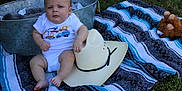 Braxton joined the competition — help win amazing prizes! baby, blanket, cowboy_hat, outdoor, grass, metal_tub, plush_toy, child, infant, clothing, foot, hand, sitting, expression, face, head, cute, summer, texture, relaxing