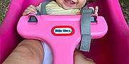 Mia is registered to the contest to win money with this photo: baby, child, toddler, swing, pink, outdoor, grass, curly_hair, smiling, happy, play, seat, toy, strap, person, face, legs, hands, daylight, nature