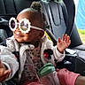 Hailee is registered to the contest to win money with this photo: toddler, child, sunglasses, car_seat, car_interior, smile, waving_hand, jacket, pink_pants, sippy_cup, cute, happy, baby, person, seatbelt, hair_bun, window, casual, indoor, portrait