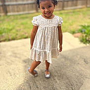 Nayeli joined the competition — help win amazing prizes! child, girl, smiling, outdoor, dress, pigtails, grass, fence, concrete, footwear, happy, portrait, young_child, person, sunlight, playful, nature, cute, summer, standing