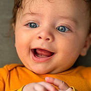 Thivyan a rejoint le concours — aidez-le/la à gagner de superbes lots ! baby, child, blue_eyes, smiling, happy, close_up, orange_clothing, hands, face, infant, cute, portrait, expression, skin, eyelashes, mouth, tongue, cheeks, hair, soft_background