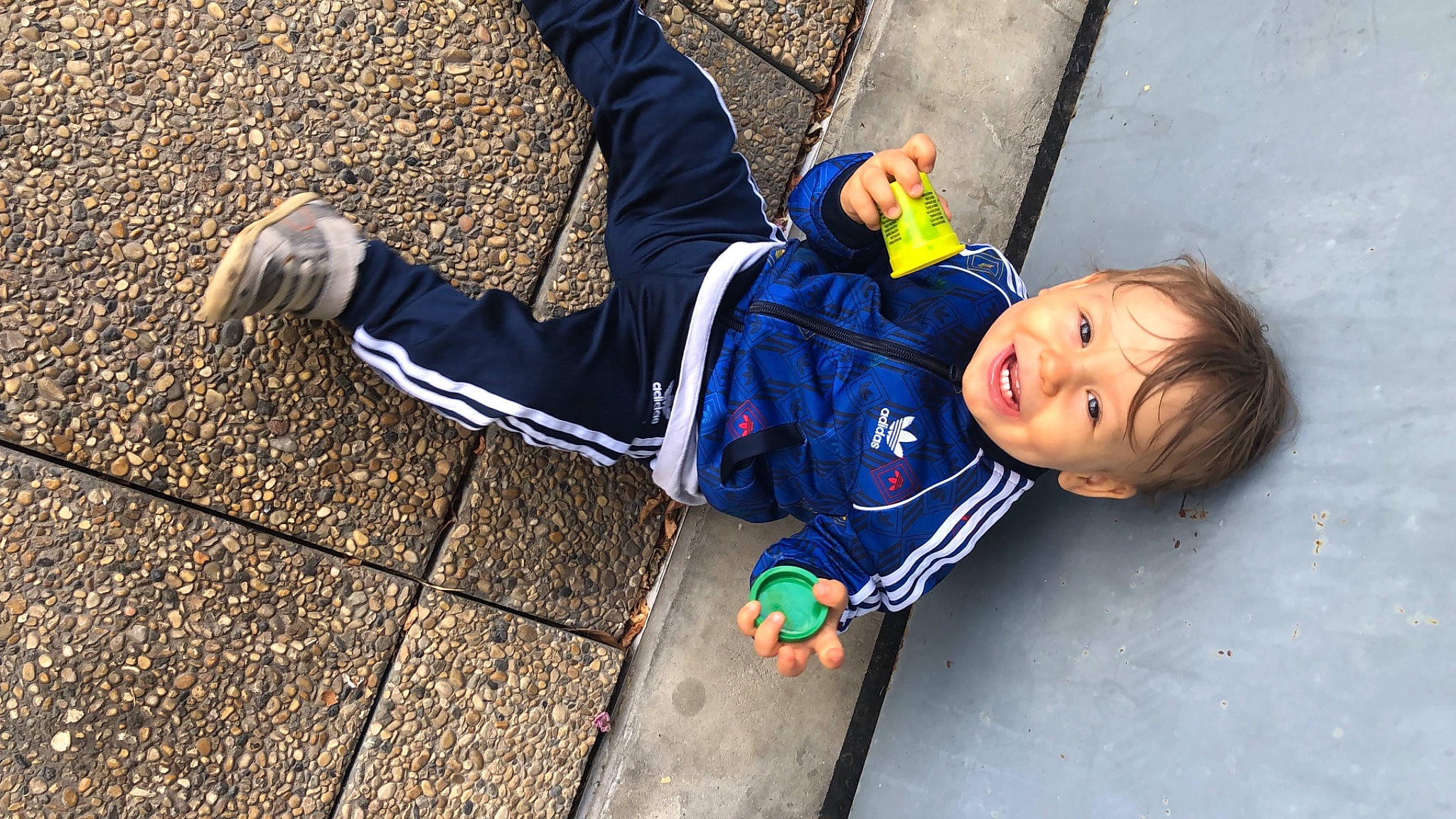 Aron participe au concours pour gagner de l'argent avec cette photo : asphalt, child, clothing, electric_blue, fun, happy, human_leg, jacket, leisure, orange, person, recreation, road, road_surface, sidewalk, sitting, snapshot, street, street_fashion, toddler