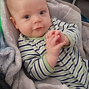 Xander is registered to the contest to win money with this photo: baby, infant, child, striped_clothing, onesie, blanket, soft_fabric, cozy, indoor, portrait, face, hands, cute, eyes, seated, cushion, comfort, young_child, person, baby_boy