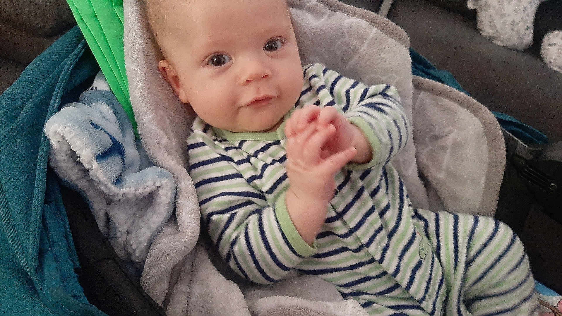 Xander is registered to the contest to win money with this photo: baby, infant, child, striped_clothing, onesie, blanket, soft_fabric, cozy, indoor, portrait, face, hands, cute, eyes, seated, cushion, comfort, young_child, person, baby_boy