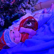 Jakari joined the competition — help win amazing prizes! baby, christmas, holiday, festive, hat, blanket, tree, decorations, indoors, infant, cute, portrait, clothing, cozy, toddler, red, blue_light, celebration, lying_down, face