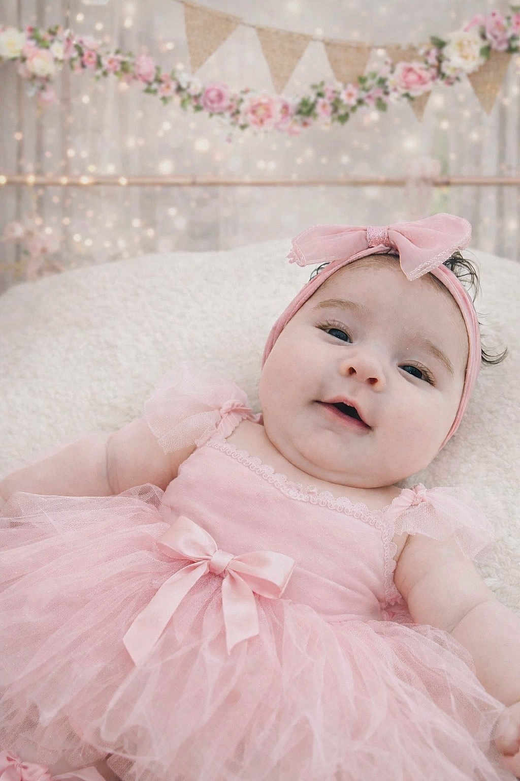 Lindsey is registered to the contest to win money with this photo: baby, baby_girl, infant, portrait, smile, headband, pink_dress, tutu, bow, blanket, soft_texture, studio_background, decorative_bunting, flower_garland, fairy_lights, close_up, cute, newborn, chubby_cheeks, cute_outfit