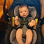 baby, black_car_seat, car_seat, child, cute, expression, face, gray_padding, hands, indoors, infant, person, safety_harness, seatbelt, sitting, small_feet, striped_clothing, toddler, wood_paneling, young_child