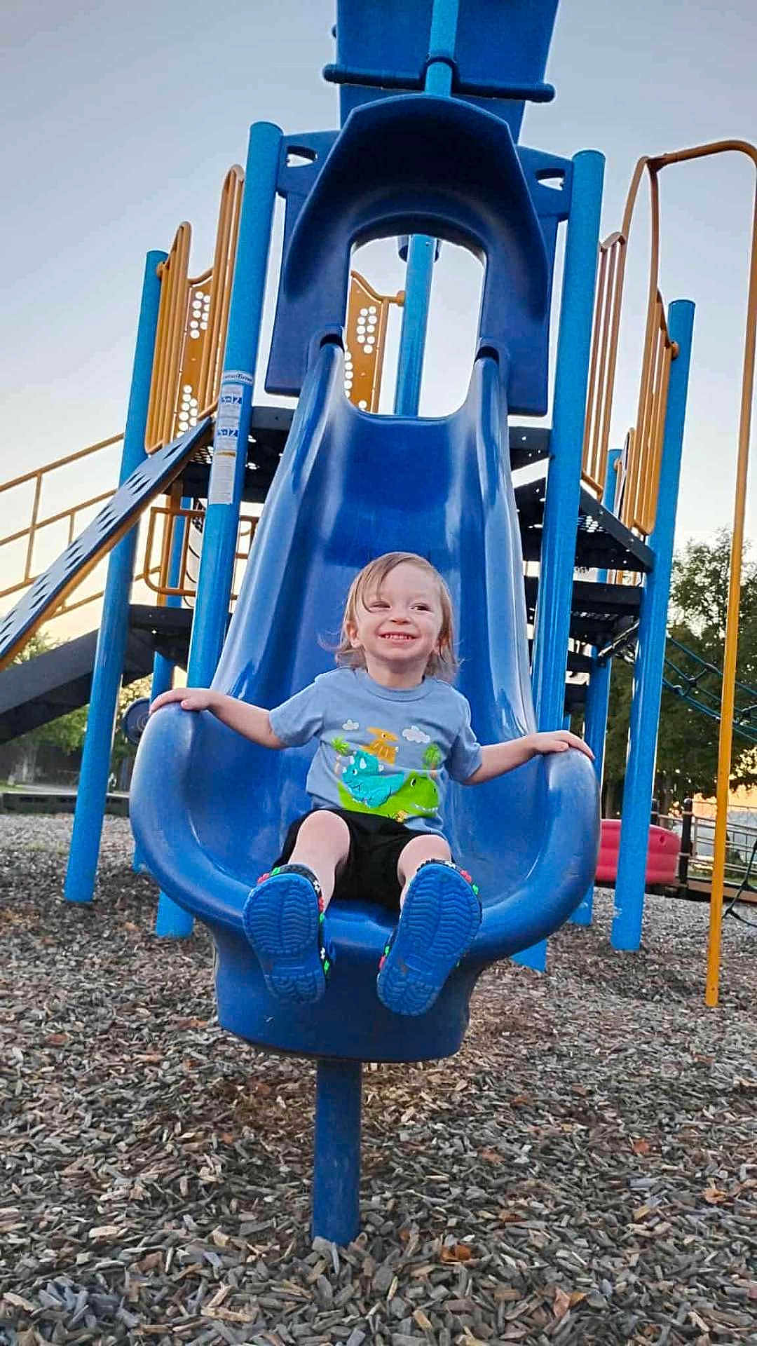 Levi joined the competition — help win amazing prizes! child, smiling, slide, playground, blue, outdoor, happy, toddler, clothing, shoes, wood_chips, play_equipment, person, fun, summer, park, daylight, casual, recreation, leisure
