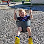 blue_shirt, chains, child, daylight, feet, fun, grass, happy, outdoor, park, playground, recreation, shorts, smiling, sunny, swing, toddler, trees, wood_chips, yellow_shoes