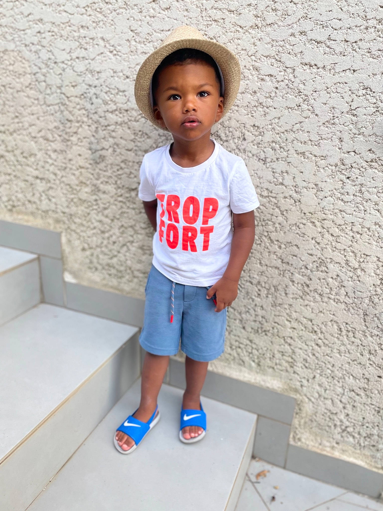 Issa participe au concours pour gagner de l'argent avec cette photo : baby_toddler_clothing, cap, child, cool, electric_blue, face, flooring, footwear, happy, hat, human_leg, knee, person, shorts, shoulder, sleeve, standing, street_fashion, sun_hat, t_shirt