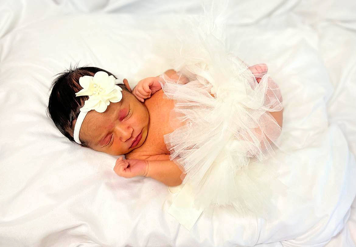 Valencia is registered to the contest to win money with this photo: baby, baby_toddler_clothing, bed, bedding, bridal_accessory, comfort, dress, embellishment, event, flash_photography, hair, happy, head, headgear, headpiece, headwear, linens, person, skin, smile