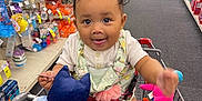 Amelia joined the competition — help win amazing prizes! baby, child, shopping_cart, plush_toy, store_aisle, cvs, smiling, tongue_out, clothing, retail, floor, person, shopping, toy, sitting, cute, happy, indoor, infant, playful