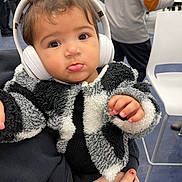 Nova joined the competition — help win amazing prizes! baby, headphones, child, indoor, person, jacket, black_and_white, fur_texture, curious, hand, seated, people, casual, clothing, face, expression, floor, chair, background, holding