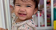 Nova joined the competition — help win amazing prizes! toddler, child, smiling, face, floral_clothing, door_frame, indoors, crib, toy, playroom, happy, person, hair, earring, cute, baby, expression, young_child, standing, room