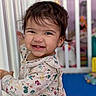 toddler, child, smiling, face, floral_clothing, door_frame, indoors, crib, toy, playroom, happy, person, hair, earring, cute, baby, expression, young_child, standing, room
