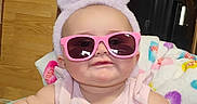 Ivery is registered to the contest to win money with this photo: baby, child, sunglasses, pink, bunny_ears, walker, toy, indoor, smile, cute, chubby_cheeks, colorful, person, headwear, infant, clothing, baby_toy, face, seat, comfort