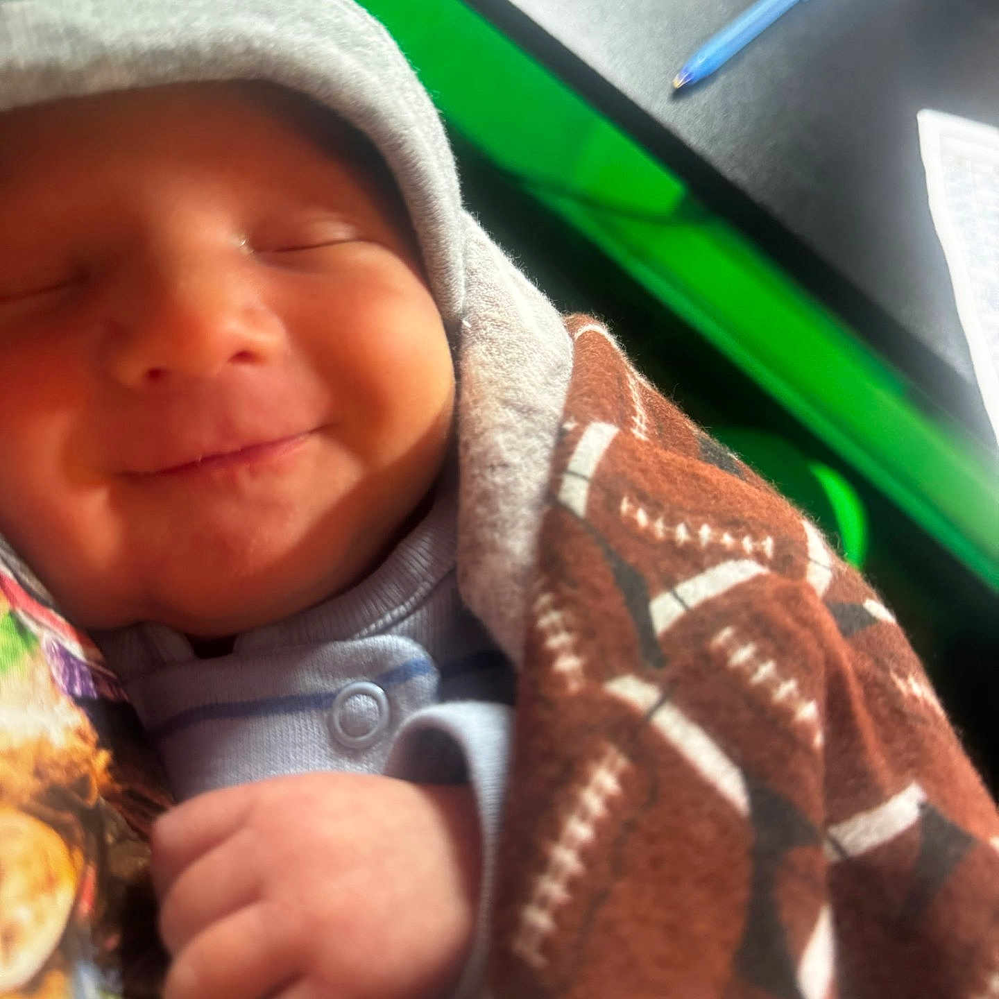 Brolee joined the competition — help win amazing prizes! baby, blanket, child, closeup, clothing, cozy, desk, face, football_pattern, hand, hood, indoor, newborn, paper, peaceful, pen, person, smiling, soft, wrapped