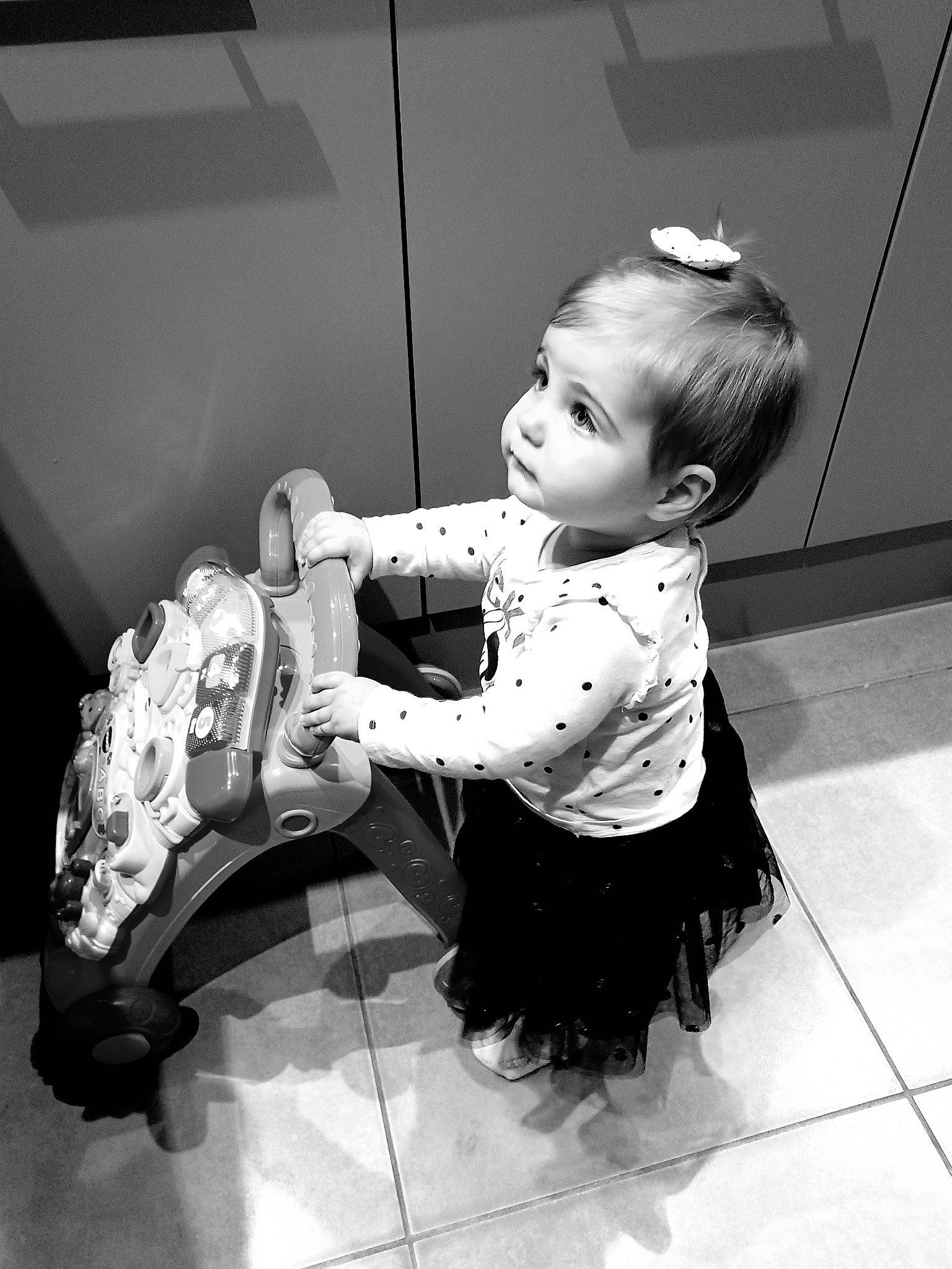 Maëlle participe au concours pour gagner de l'argent avec cette photo : arm, baby, baby_toddler_clothing, black_and_white, child, dress, flash_photography, flooring, fun, hair, hand, human_body, human_leg, leg, monochrome, monochrome_photography, person, sitting, standing, style