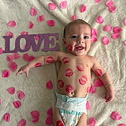 Giovanni is registered to the contest to win money with this photo: baby, infant, child, diaper, lipstick_marks, kiss_marks, pink_petals, love_sign, blanket, smiling, happy, face, eyes, arm, bracelet, lying_down, portrait, soft_texture, cute, closeup