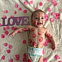 baby, infant, child, diaper, lipstick_marks, kiss_marks, pink_petals, love_sign, blanket, smiling, happy, face, eyes, arm, bracelet, lying_down, portrait, soft_texture, cute, closeup
