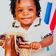 Jaleel is registered to the contest to win money with this photo: background_blur, child, colorful, cute, dreadlocks, face, hand, happy, indoor, person, playful, portrait, rocking_horse, smiling, studio, toddler, toy, white_clothing, wooden_toy, young_child