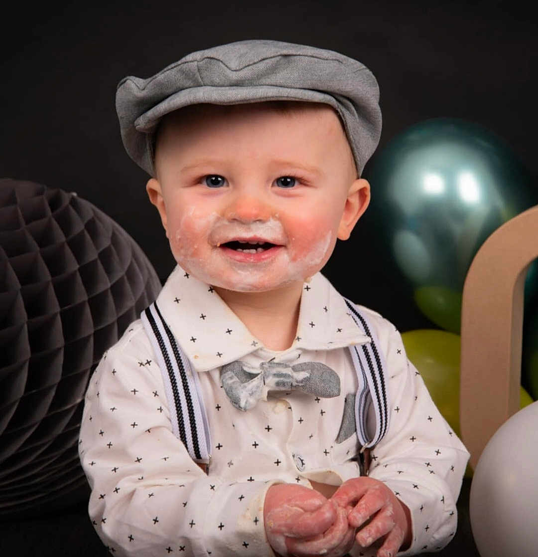 Lézio participe au concours pour gagner de l'argent avec cette photo : baby, boy, smiling, face_paint, cake_frosting, hat, cap, shirt, bow_tie, suspenders, hands, party, balloons, decoration, celebration, portrait, cute, child, happy, indoors