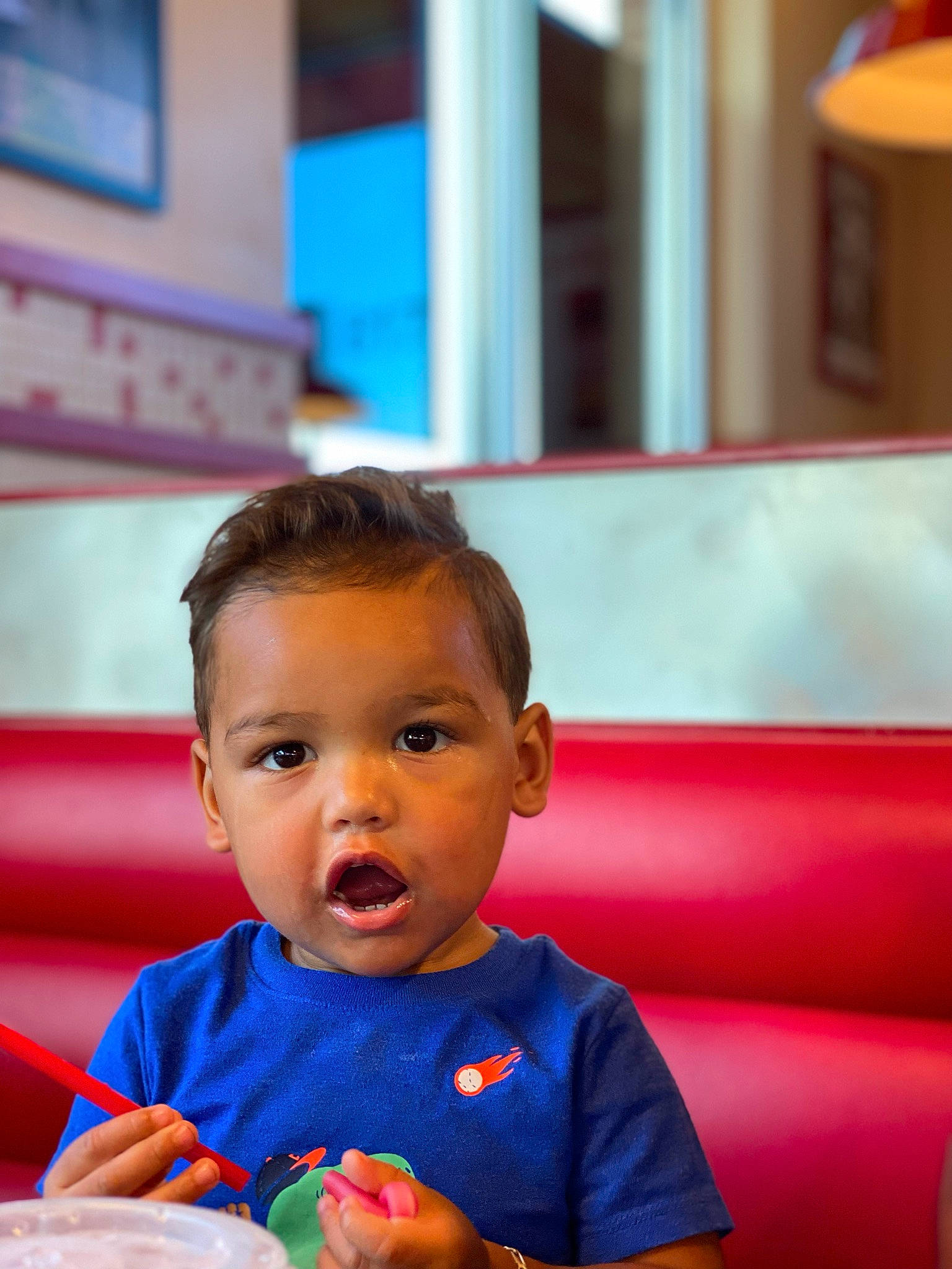 Renzo is registered to the contest to win money with this photo: baby, blue, child, comfort_food, fruit, fun, happy, lamp, leisure, nose, person, recreation, room, sitting, surprise, t_shirt, toddler, travel, vacation