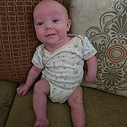 Alex joined the competition — help win amazing prizes! baby, infant, onesie, couch, pillow, home, furniture, smile, face, sitting, child, cute, pattern, textile, skin, legs, arms, indoors, person, comfortable