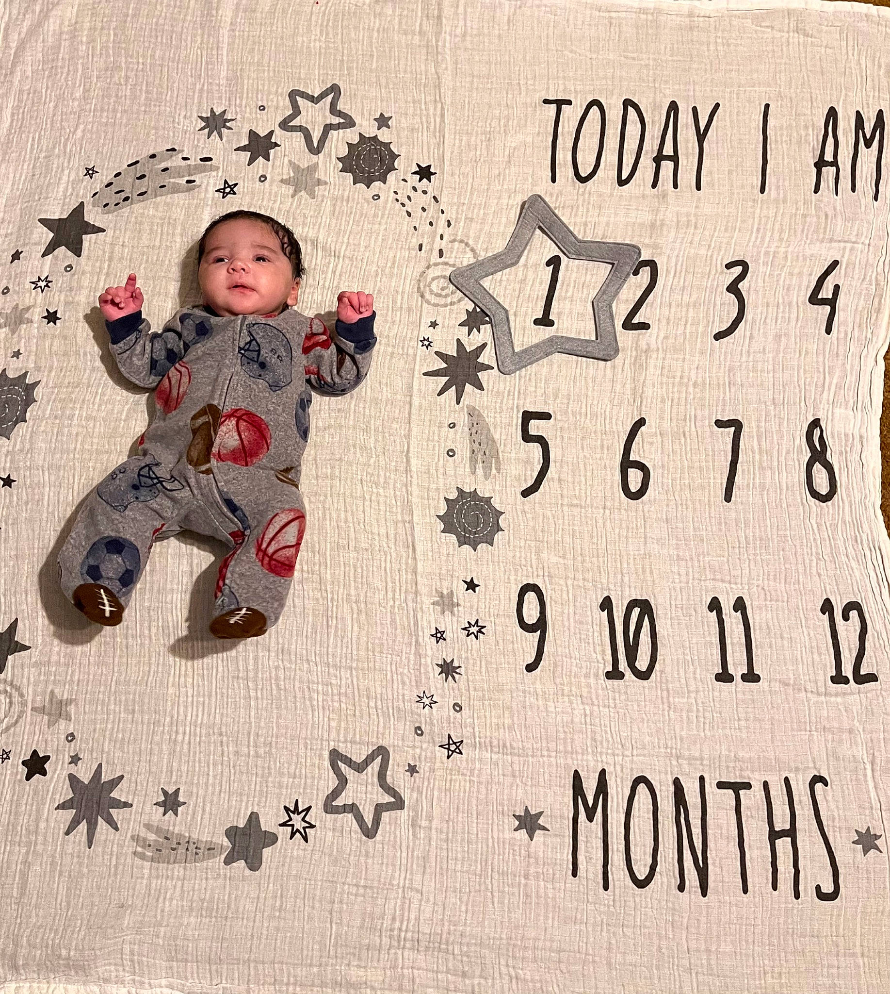 Xavier is registered to the contest to win money with this photo: art, baby, baby_toddler_clothing, craft, creative_arts, design, facial_expression, flooring, font, handwriting, happy, illustration, number, paper, paper_product, pattern, person, rectangle, sleeve, toddler