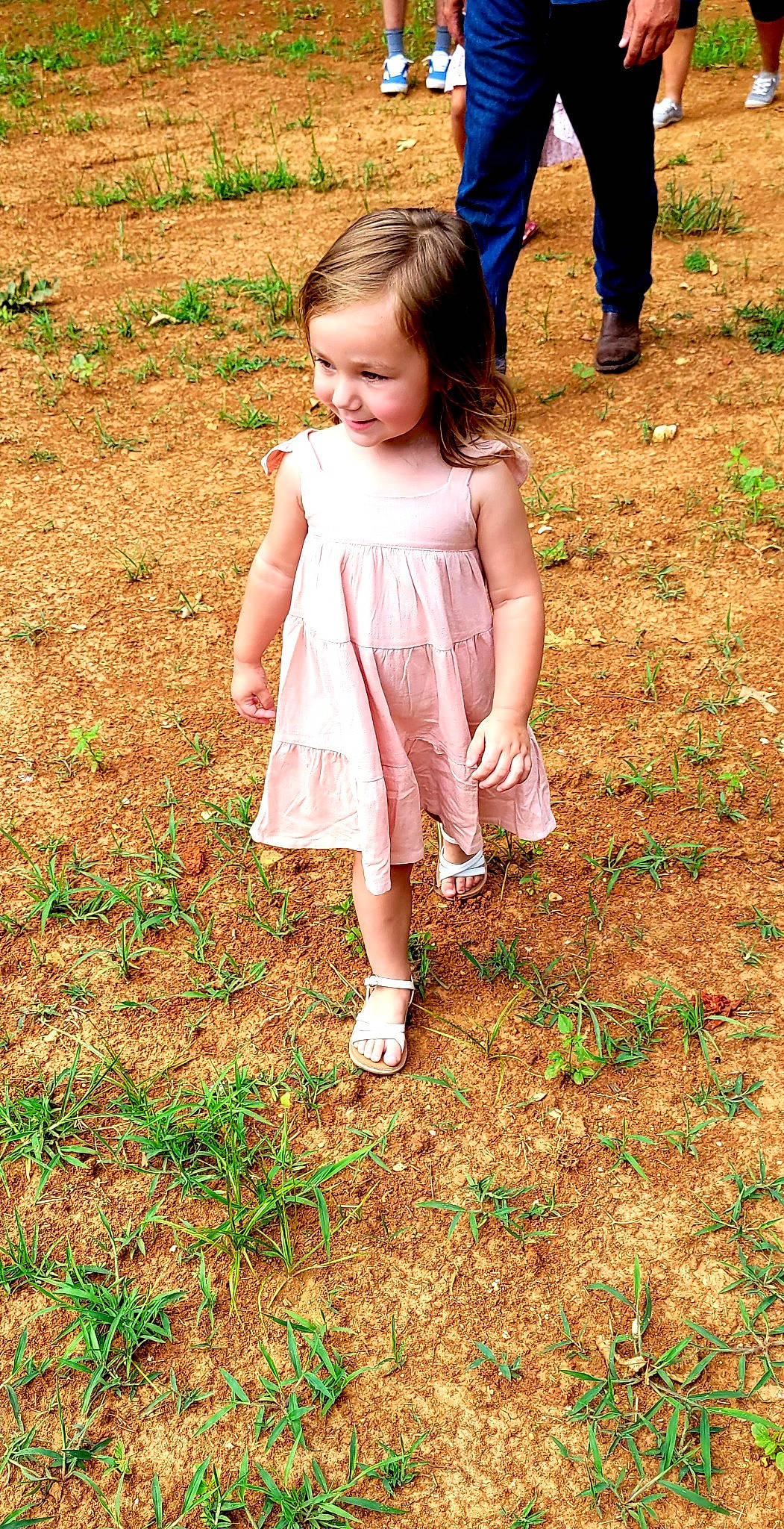 Mackenzie is registered to the contest to win money with this photo: baby_toddler_clothing, barefoot, dress, face, fun, gesture, grass, grass_family, happy, human_leg, joy, lawn, leaf, leg, nature, people_in_nature, person, plant, sandal, toddler