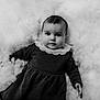 baby, child, portrait, black_and_white, dress, lace_collar, face, eyes, hand, fluffy_background, soft_texture, cute, infant, lying_down, monochrome, young, person, studio, innocence, calm