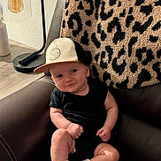 Hudson joined the competition — help win amazing prizes! baby, child, infant, sitting, chair, leather_chair, baseball_cap, sneakers, black_clothing, leopard_print, cushion, lamp, indoor, portrait, fashion, cute, smiling, face, furniture, home_decor