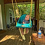 Koen joined the competition — help win amazing prizes! baby, swing, porch, wooden_floor, baby_clothing, outdoor, nature, trees, chair, table, water_bottle, stove, rope, wooden_roof, window, door, shoes, towel, expression, furniture