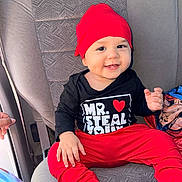 Gohan joined the competition — help win amazing prizes! baby, black_shirt, blanket, car_seat, child, clothing, cute, face, hand, happy, infant, interior, person, portrait, red_hat, red_pants, seat, sitting, smiling, text_on_clothing