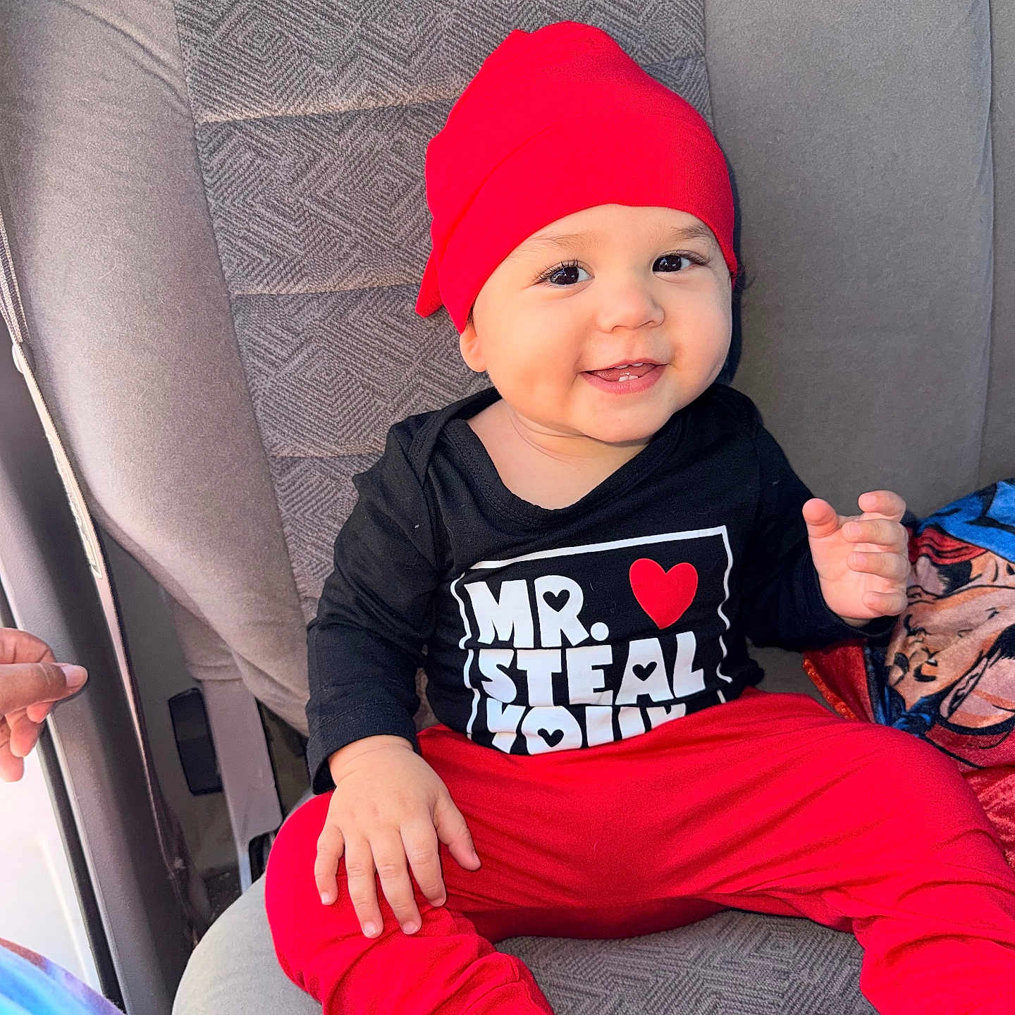 Gohan joined the competition — help win amazing prizes! baby, black_shirt, blanket, car_seat, child, clothing, cute, face, hand, happy, infant, interior, person, portrait, red_hat, red_pants, seat, sitting, smiling, text_on_clothing
