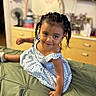 Maricela is registered to the contest to win money with this photo: child, toddler, girl, smiling, braided_hair, blue_dress, bed, green_bedspread, indoor, furniture, dresser, mirror, room, person, happy, portrait, casual, cute, playful, home