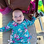 baby, smile, blue_eyes, floral_clothing, cushion, bag, pink, green, happy, infant, child, diaper, lying_down, cute, outdoor, bright, colorful, portrait, baby_girl, playful