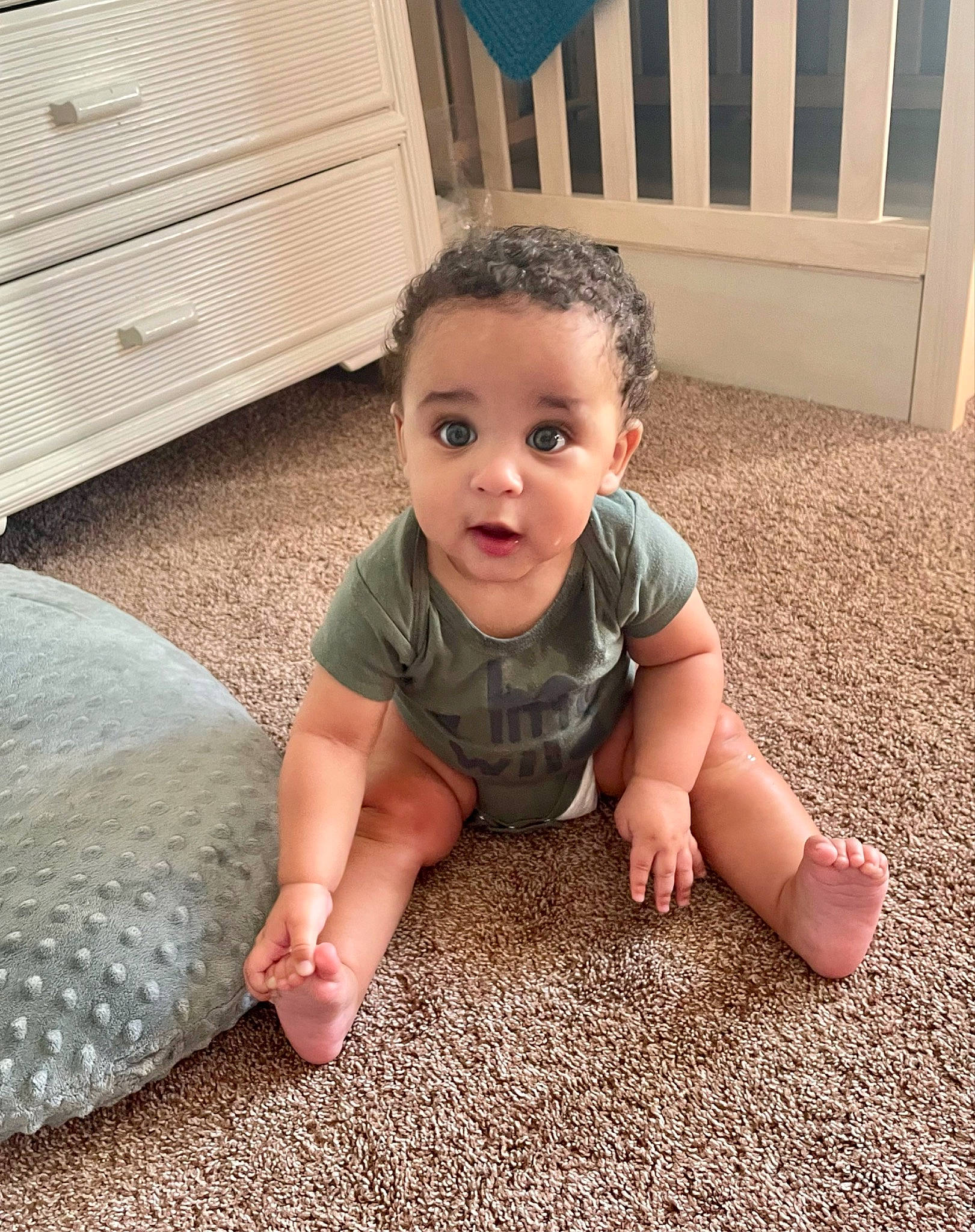 Myles is registered to the contest to win money with this photo: baby, baby_toddler_clothing, bean_bag, cabinetry, child, comfort, crawling, drawer, floor, flooring, foot, fun, grey, hairstyle, happy, hardwood, human_leg, person, sitting, surprise