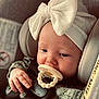 baby, pacifier, car_seat, headband, bow, infant, child, seatbelt, close_up, portrait, clothing, hand, sitting, indoors, cute, young_child, soft_lighting, face, expression, comfort