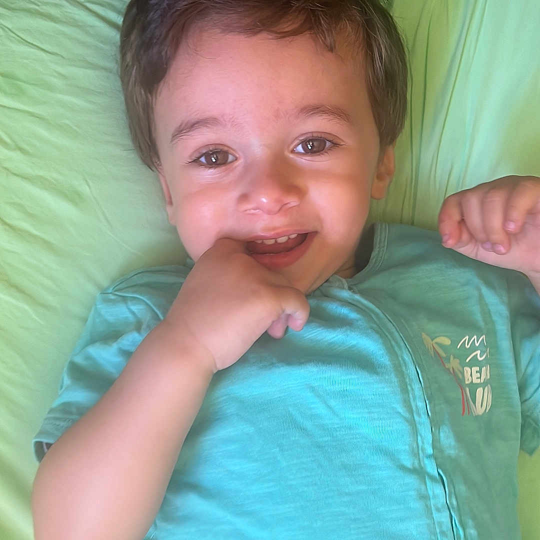 Gabriel Assaf a rejoint le concours — aidez-le/la à gagner de superbes lots ! baby, casual_clothing, child, cute, face, hand, happy, head, indoors, lying_down, person, pillow, portrait, relaxed, skin, small_child, smiling, toddler, turquoise_shirt, young_child