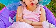 Mylah is registered to the contest to win money with this photo: child, girl, fairy_wings, pink_dress, sparkles, pigtails, chair, outdoor, grass, footwear, bracelet, pouty_face, cute, portrait, costume, summer, playful, fashion, young, person