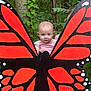 baby, child, butterfly_wings, forest, greenery, outdoor, nature, wood, tree_trunk, leaves, playful, imaginative, cute, person, portrait, colorful, art, hand, pink_shirt, summer