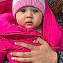 baby, child, hat, pink_jacket, pom_pom, hand, nail_polish, pen_marks, forest, car_interior, winter_clothing, cozy, cute, portrait, outdoor_background, warm_clothes, infant, person, face, expression