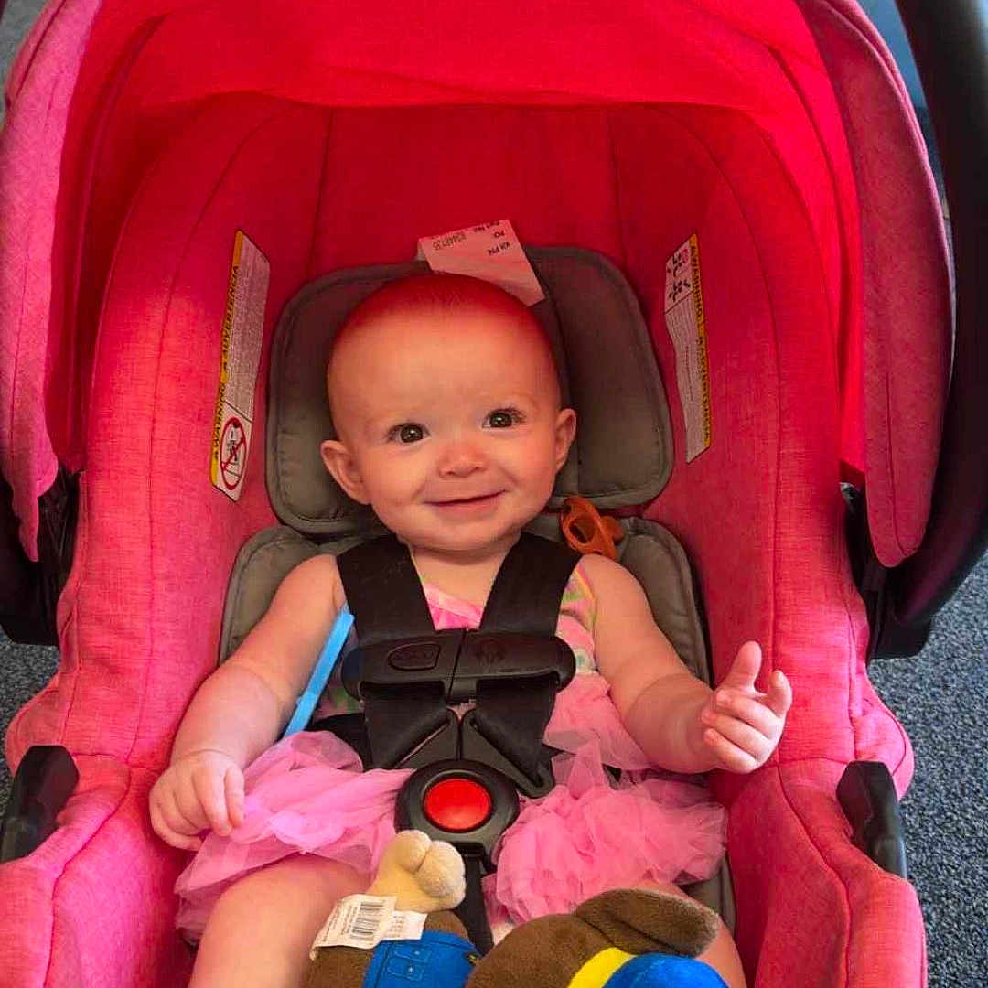 Addalynn Elizabeth is registered to the contest to win money with this photo: baby, barefoot, car_seat, child, child_safety, cute, dress, face, floor, happy, head, indoor, infant, person, pink_car_seat, plush_toy, seat_belt, smiling, toy, young_child